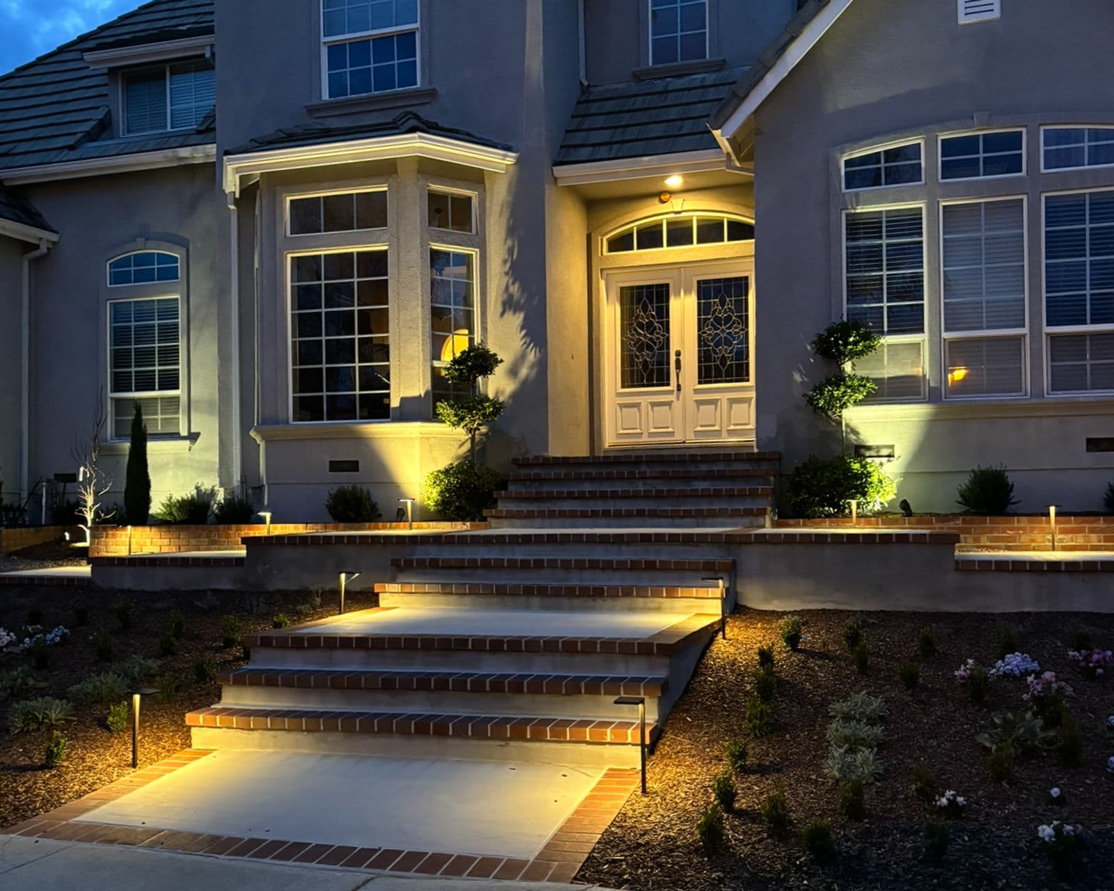 Front entry steps and planting beds illuminated with low-voltage landscape lighting