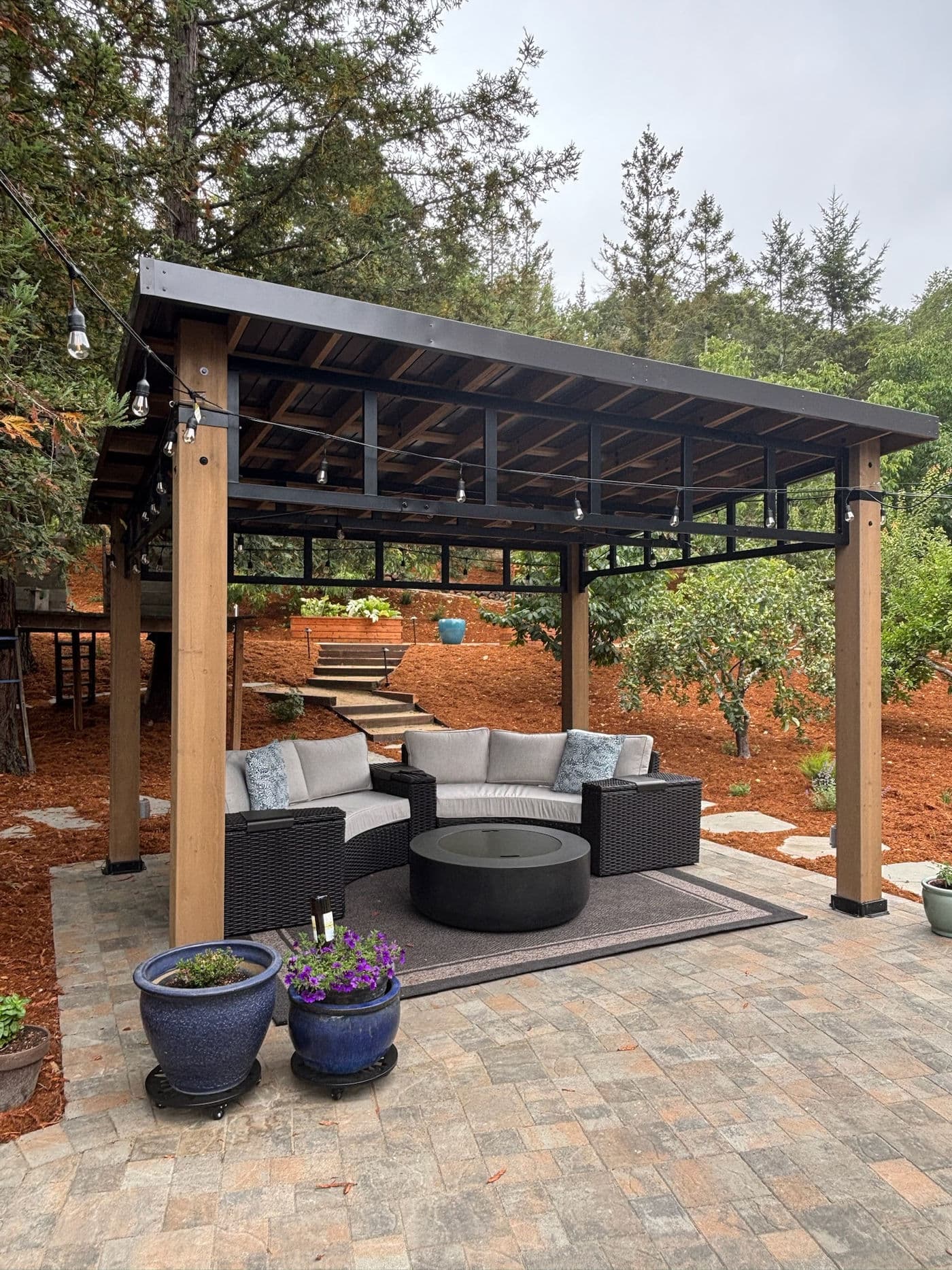 Wood and steel pergola sheltering a seating area on a paver patio
